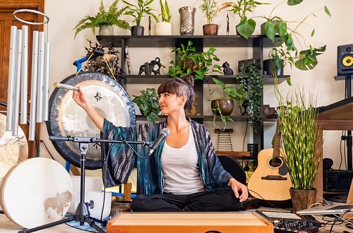 Musician in studio with various musical instruments, plants, and audio equipment